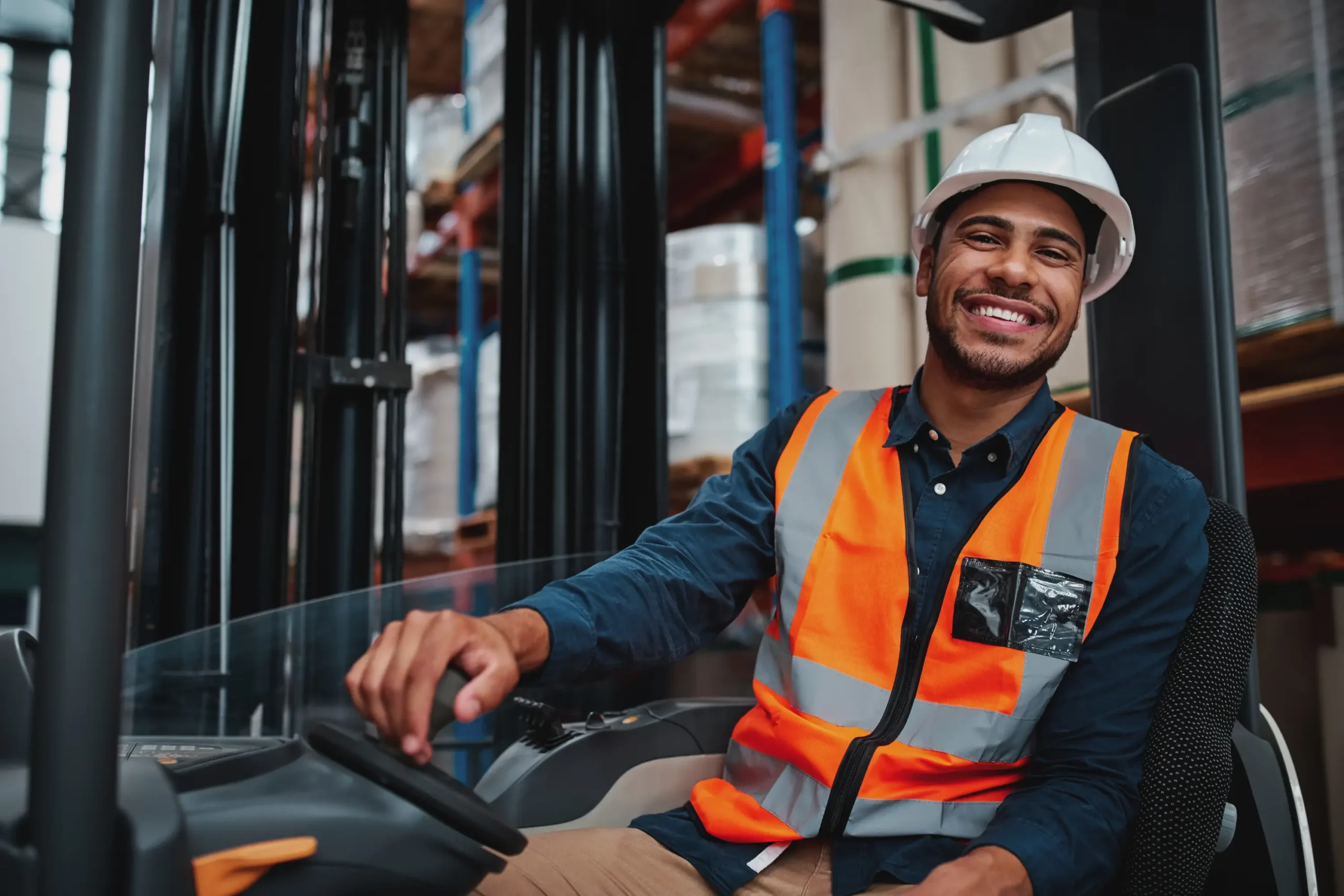 Man wearing a hard hat and orange safety vest sits on a forklift he bought with commercial finance from Borrow bridge